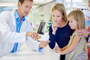 Pharmacist counseling mom with child at counter about medication.